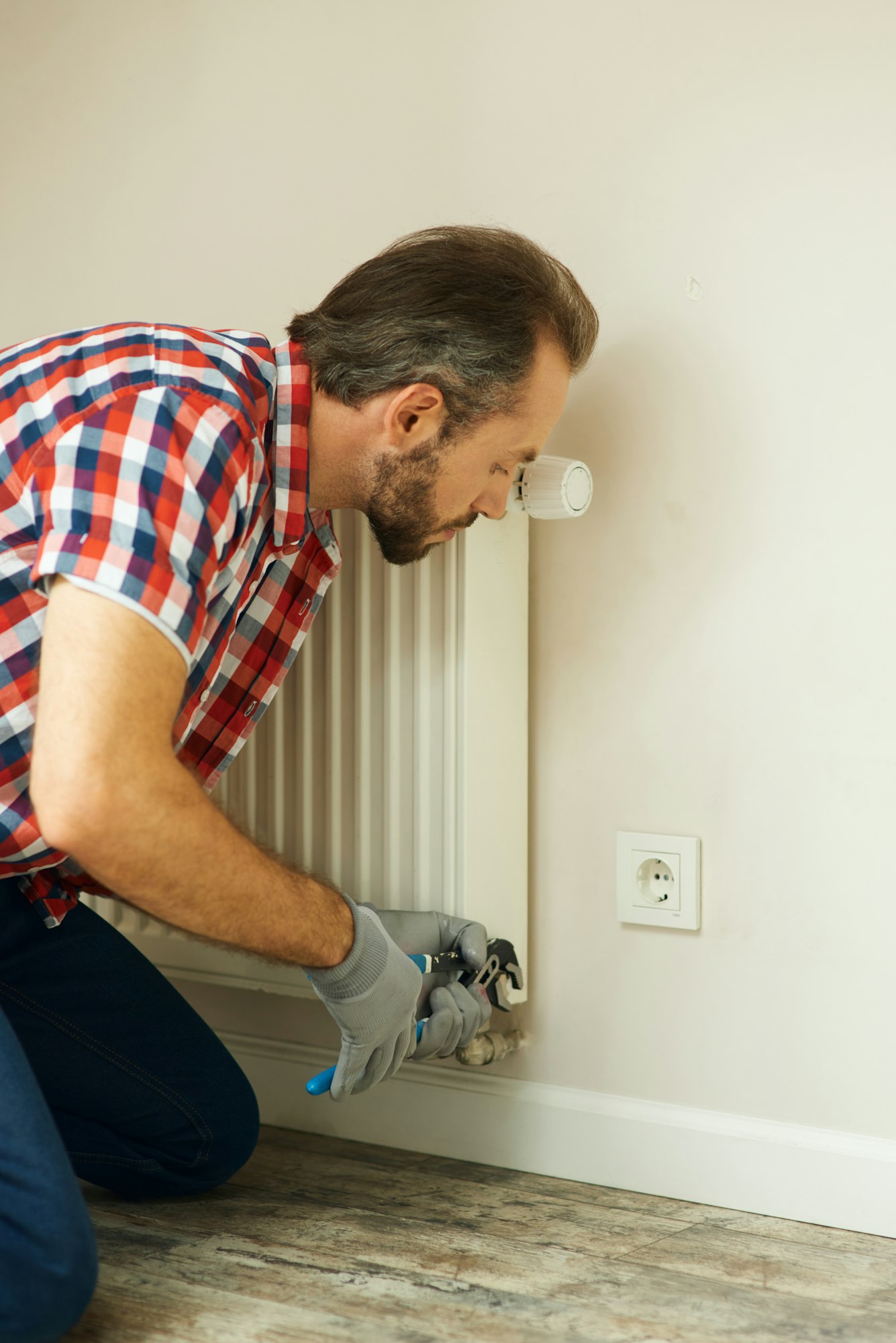 Quality help. Handyman using pipe wrench while repairing radiator battery in the room. Heating